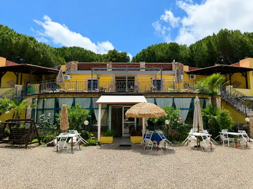 Esterno dell'Hotel Paradiso con la sua facciata gialla, la terrazza e i tavoli in giardino